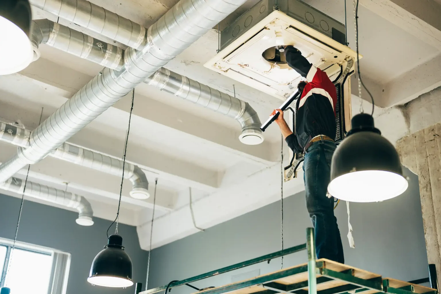 technician-repairs-ceiling-unit-in-commercial-spac-YDQ3VG6