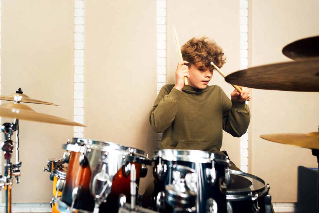 Teen banging on a drum kit. Lesson at the music school.