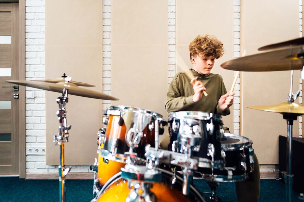 Teen boy playing drum kit. Lesson at the music school.
