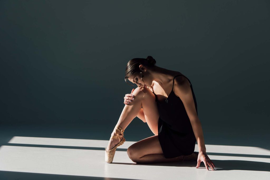 beautiful ballerina in black dress sitting in sunlight