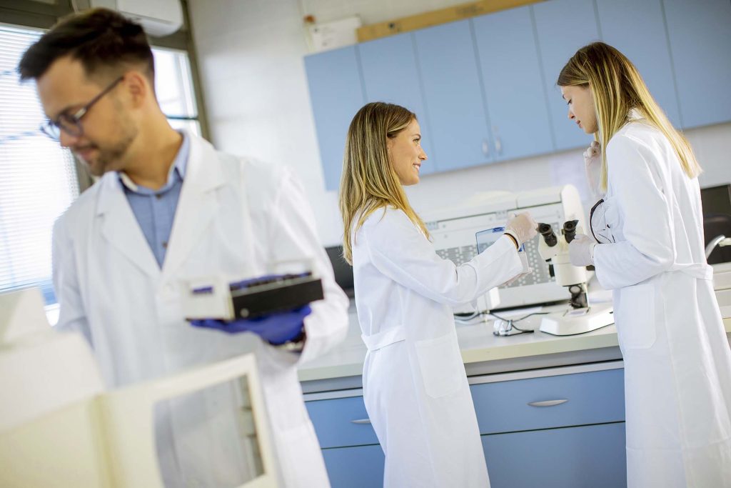 Handsome researcher in protective workwear standing in the laboratory and analyzing liquid samples