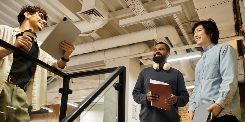 Three colleagues share ideas and insights while standing in a bright workspace filled with energy.