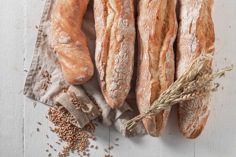 Rustic baguettes baked in bakery. Country kitchen or bakery. Pieces of baguette.