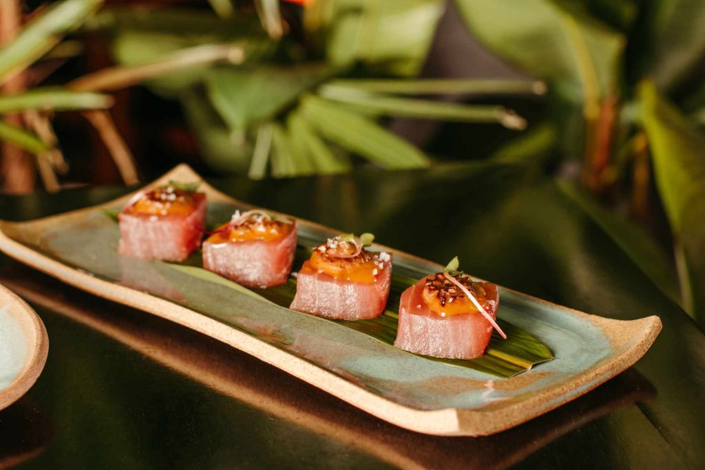 A white plate filled with a variety of sushi rolls and served against a blurred background