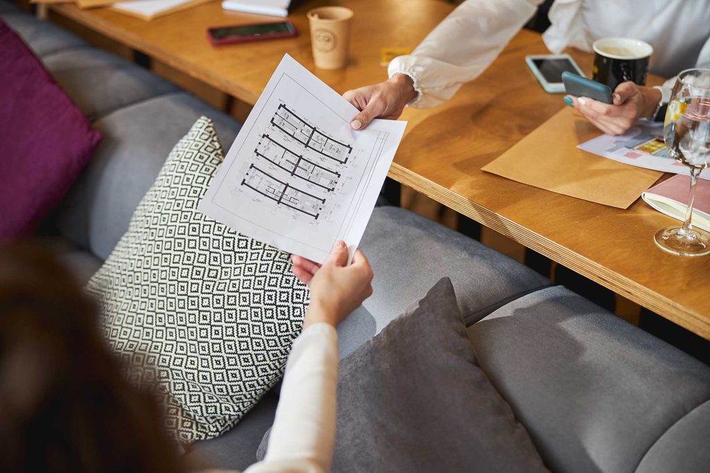 Close up of female hands holding sheet of paper with architectural drawing for business project