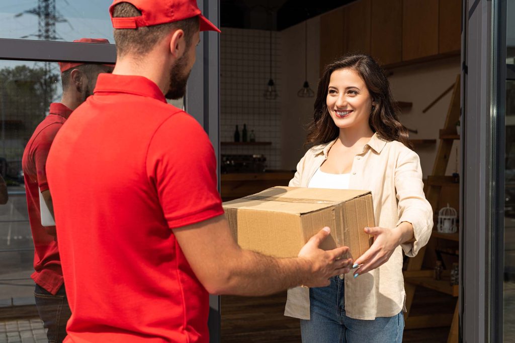 delivery man giving cardboard box to happy woman