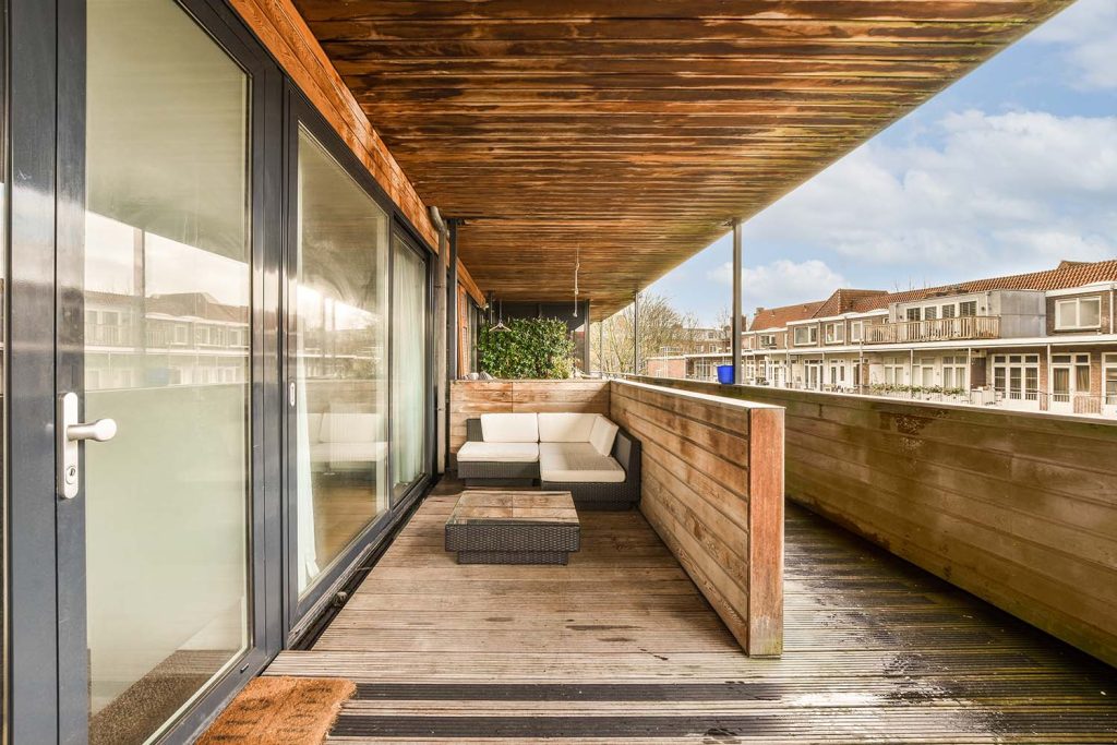 an outside area with wooden flooring and glass doors on the side of a building that is covered in wood planks