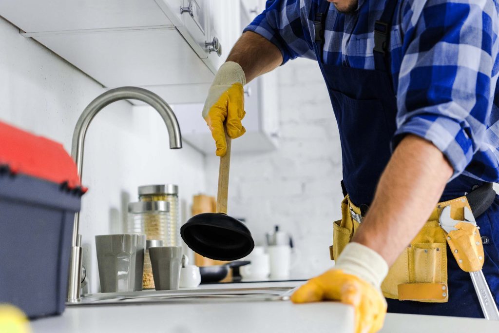 cropped view of repairman holding plunger in kitchen