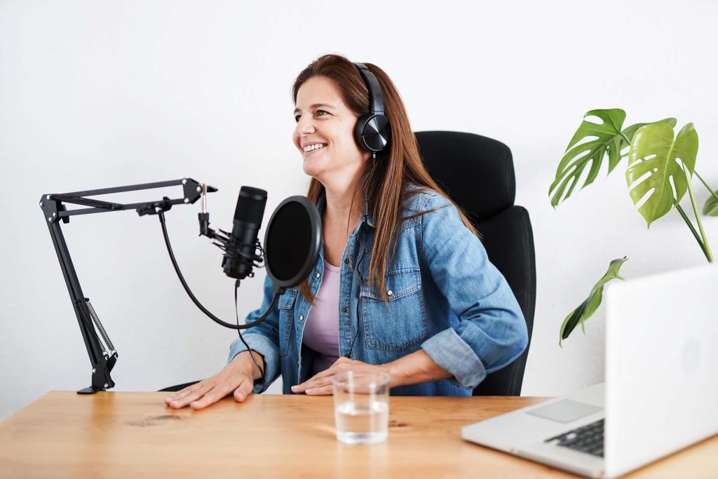 Mature woman recording a podcast inside studio