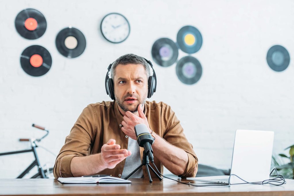 thoughtful radio host in headphones recording podcast in broadcasting studio