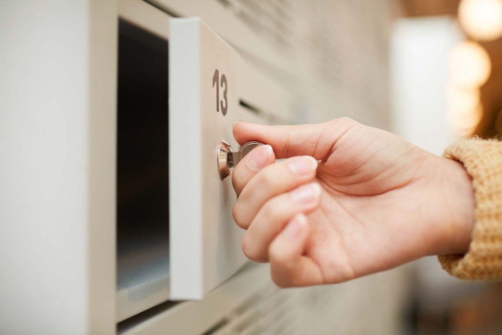 Hand of office worker shutting door of personal safe to lock it at the end of working day