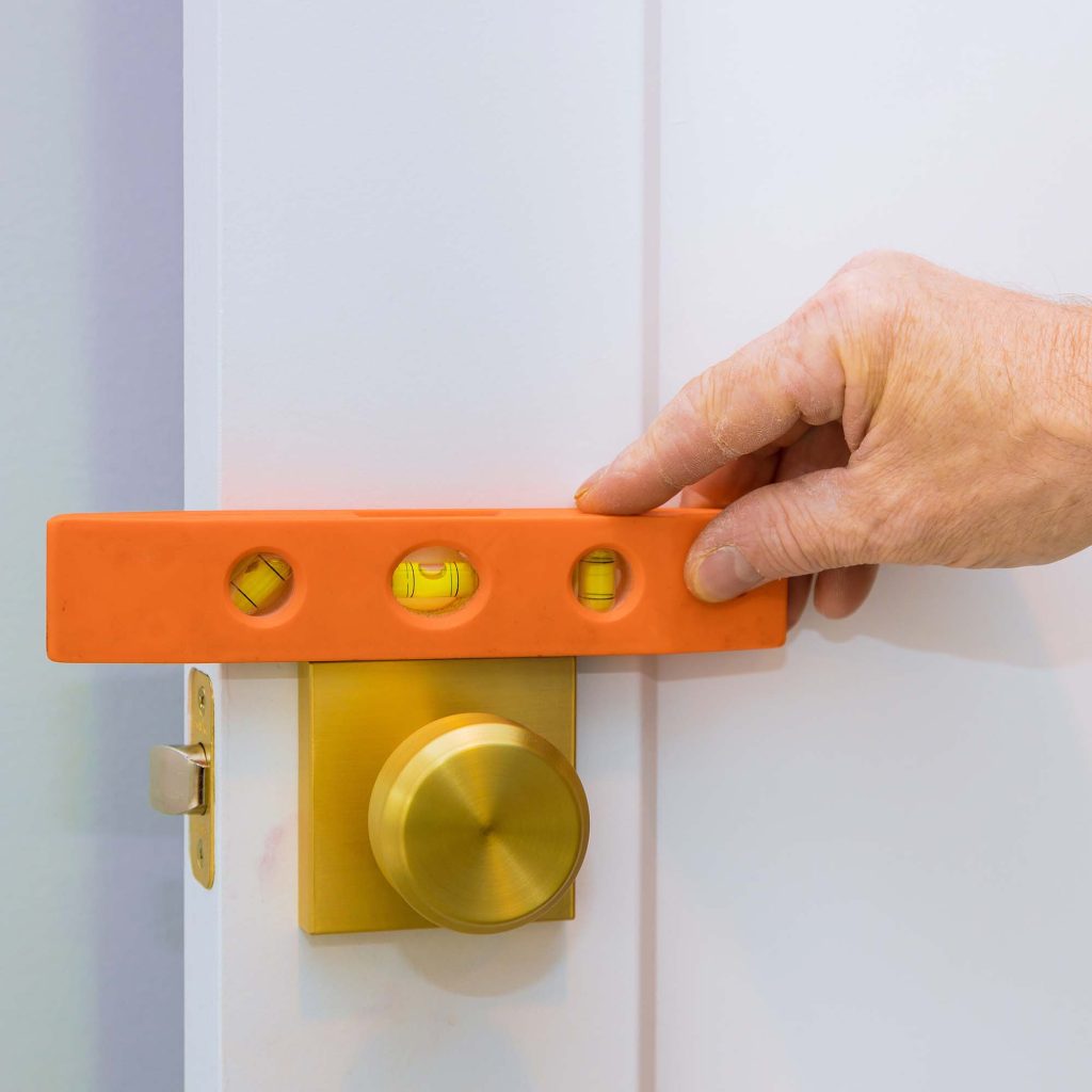 Male carpenter fixing lock in door with home hand close-up.