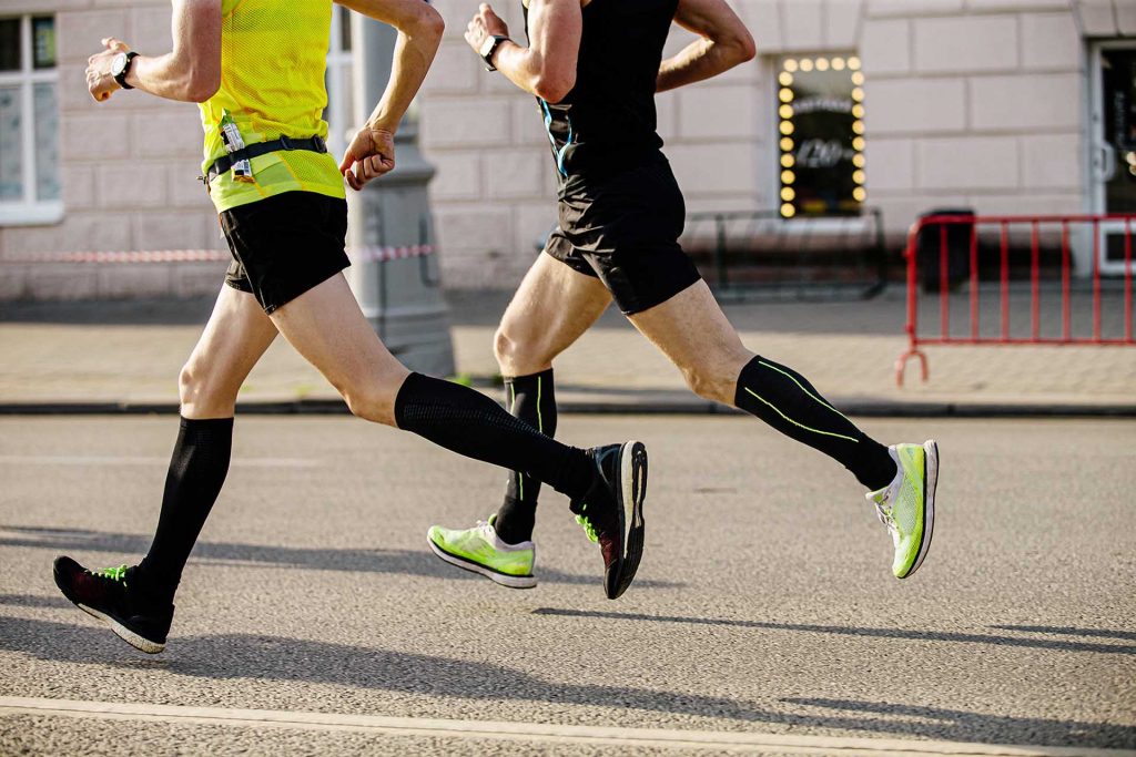two men runners in compression socks running down city street