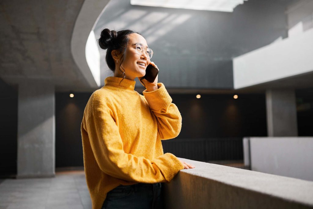 Phone call, networking and mockup with an asian woman talking while standing in a hallway. Mobile, .
