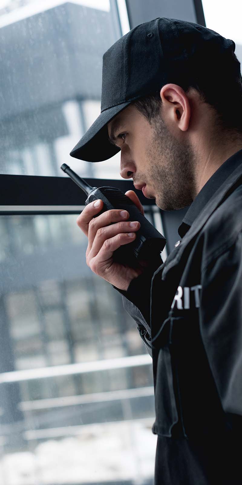 handsome guard in black uniform talking on walkie-talkie