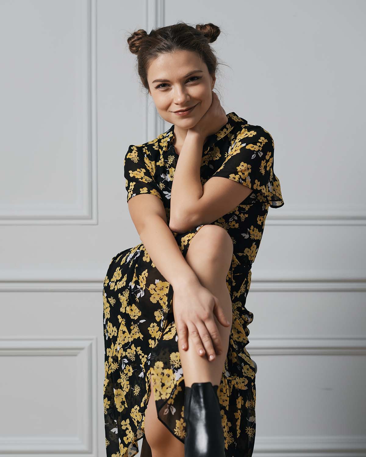 Attractive young woman in a floral dress sitting on a chair in the studio
