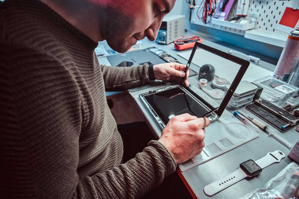 The technician repairs a broken tablet computer in a modern repair shop