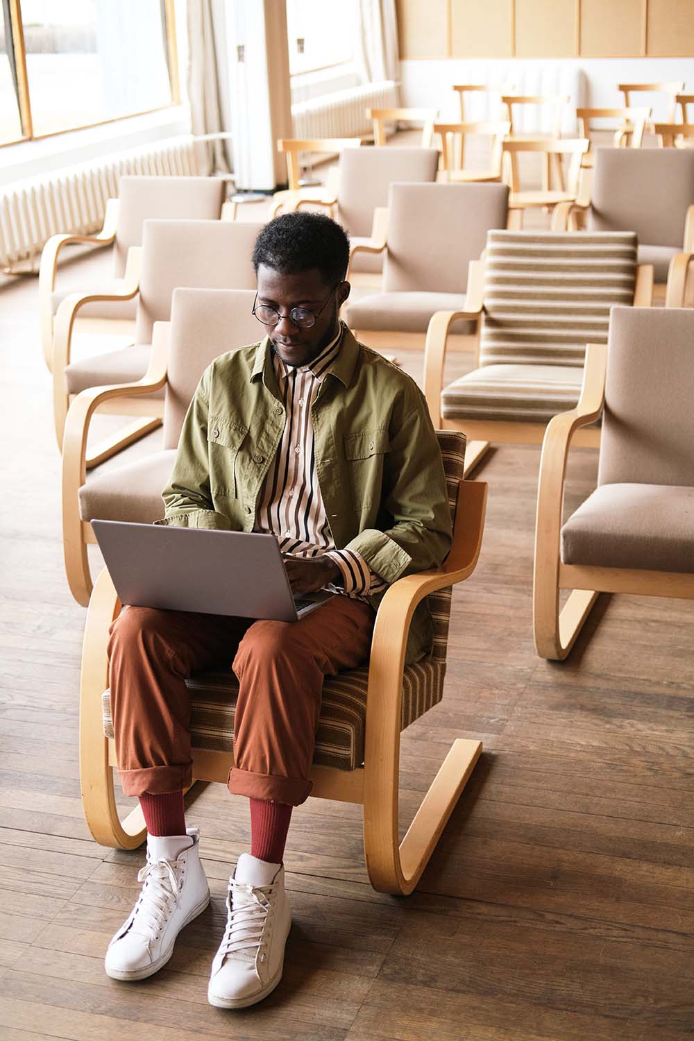 African businessman sitting on chair and working on laptop in empty conference hall